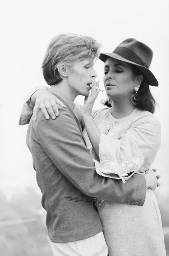 Singer David Bowie sharing a cigarette with actress Elizabeth Taylor in Beverly Hills, 1975. It was the first occasion that the pair had met. (Photo by Terry O'Neill/Getty Images)